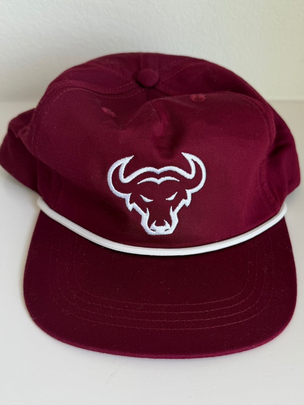 Maroon and white bull rope cap